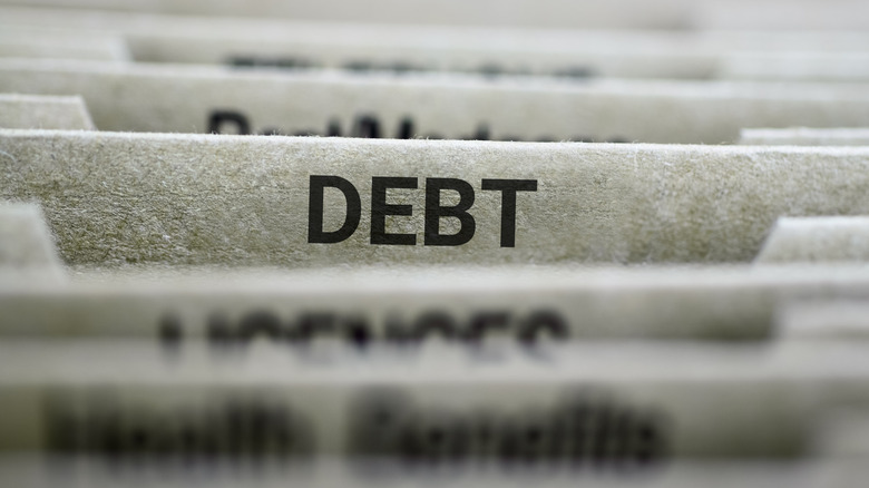 A close-up of file folders with a focus on one tab labeled 'DEBT'.