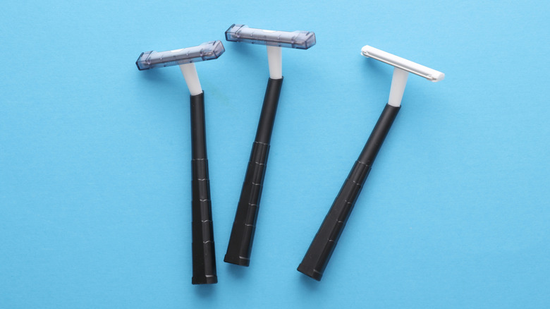 Three disposable razors against a blue backdrop