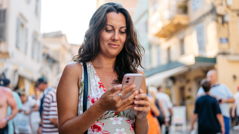 A mature woman navigating the streets of Corfu, Greece with her phone.