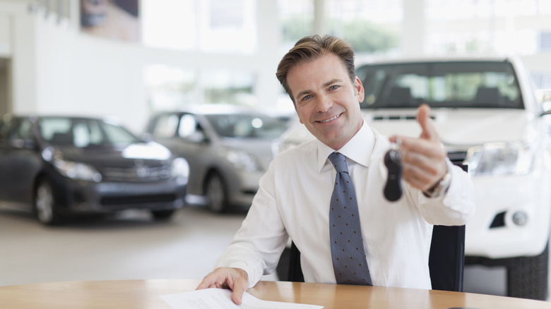 A car salesman holding up car keys