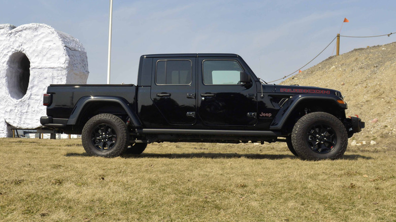 A black Jeep Gladiator parked in a grassy field.