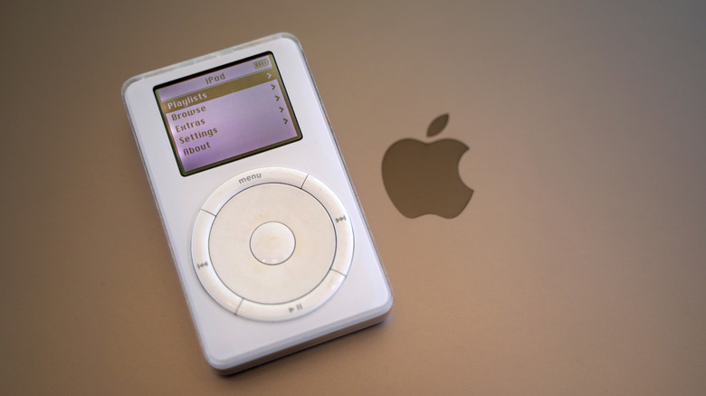 A 1st generation iPod laying on top of a Macbook laptop.
