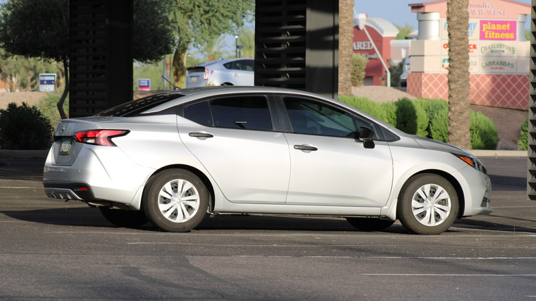 A light grey Nissan Versa parked in a parking lot.