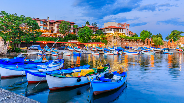 Fishing boats in the harbour at dusk in Burgas, Bulgaria with seaside homes in the background