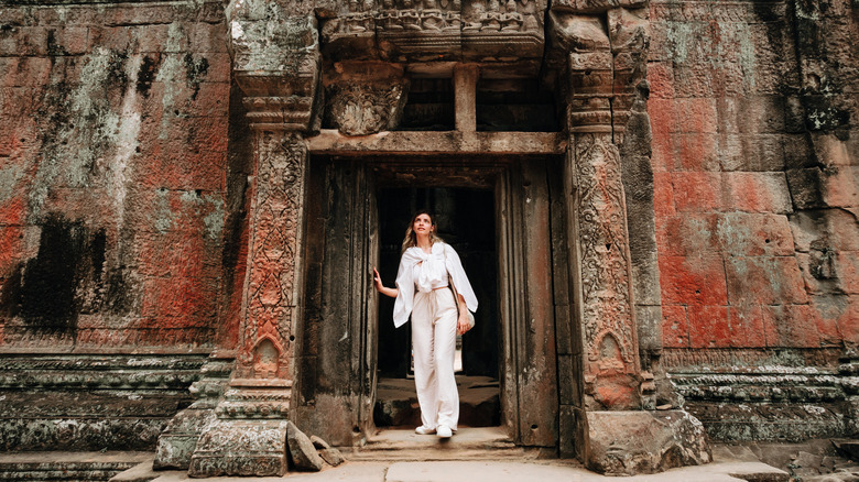 A traveler exploring an entrance at the ruins of Cambodian landmark Angkor Wat in Siem Reap
