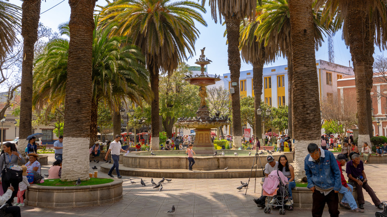 Luis de Fuentes square in Tarija Bolivia with fountain, palm trees and people enjoying the park