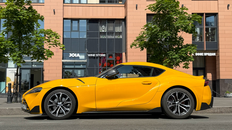Yellow sport car Toyota Supra GR V (A90, A91) MK 5 in a parking lot on street.