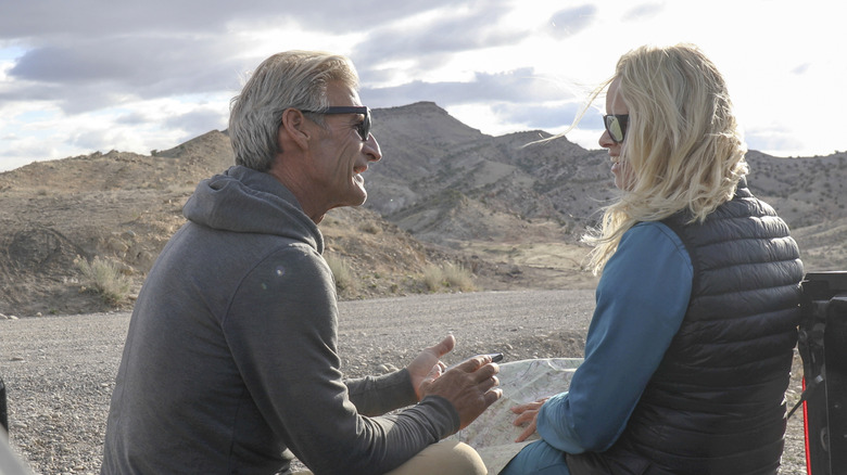 A mature couple talking with mountains in the background.