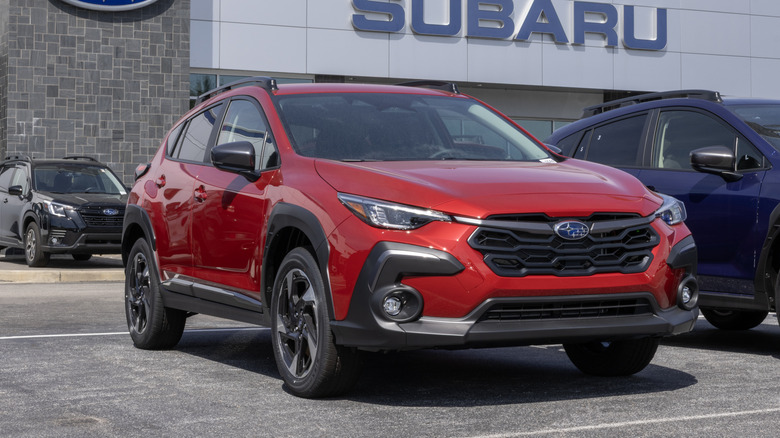 A red Subaru Crosstrek Limited AWD Compact SUV at a dealership.