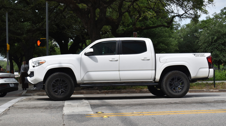 A white Toyota Tacoma driving down the street.
