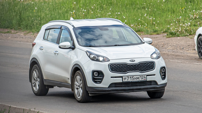 White Kia Sportage driving on the road.