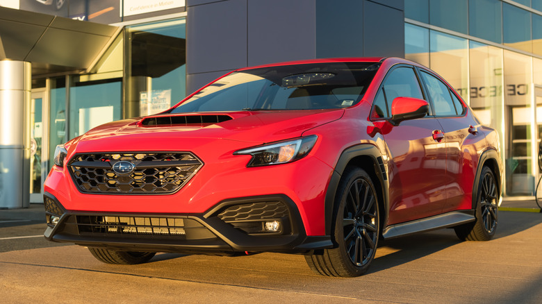 A red Subaru Impreza WRX sedan at a Subaru dealership.