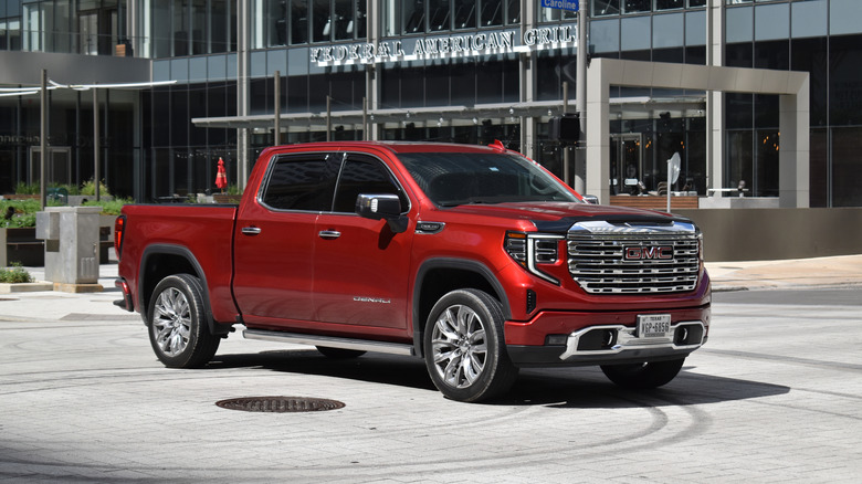 A red GMC Sierra 1500 pick-up truck cruising in the downtown financial district of the city.