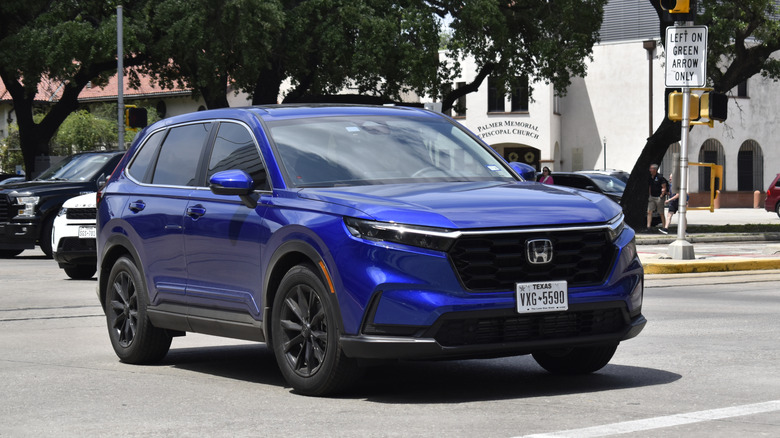 A blue Honda CR-V Hybrid luxury SUV, turns ahead of the competition, near Hermann Park in the downtown financial district.