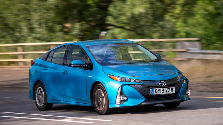 A blue Toyota Prius hybrid electric car driving on a British road.