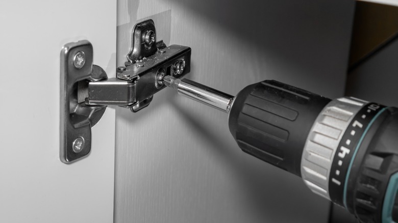 power drill installing a soft-close hinge