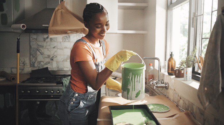 woman pouring green paint in a kitchen