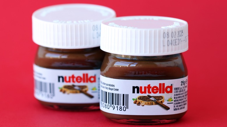 Close up of two small jars of Nutella against red background