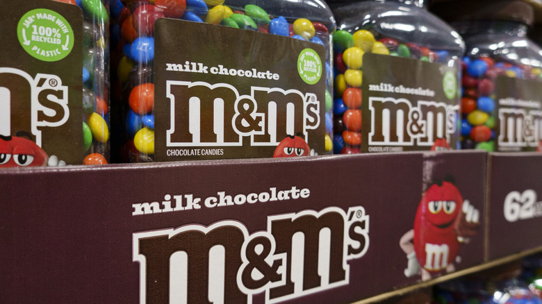 Close up of multiple large clear containers of rainbow colored M&M candies