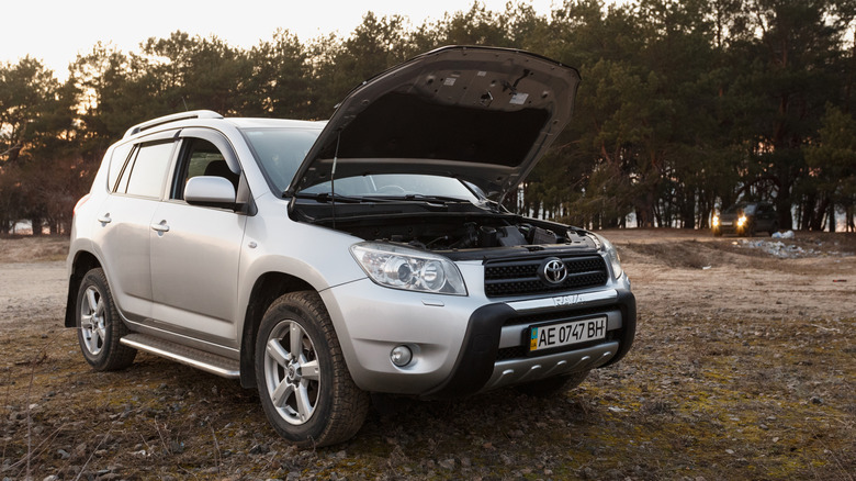 A grey 2006 Toyota RAV4 with an open hood in a field.