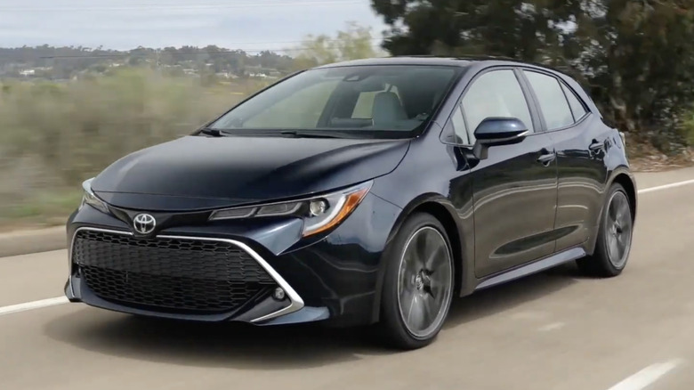 A black 2021 Toyota Corolla Hatchback driving on a rural street