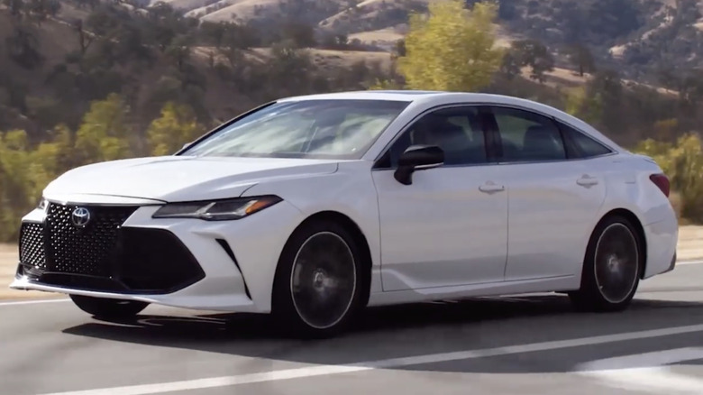 A white 2022 Toyota Avalon passing through a mountain range