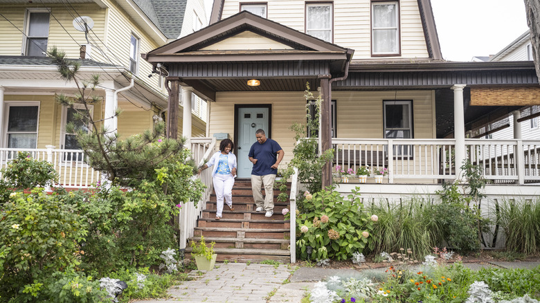 A senior couple walking down the stairs in front of their home.