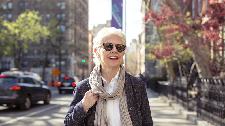 A happy senior woman wearing sunglasses walking down a street in New York City