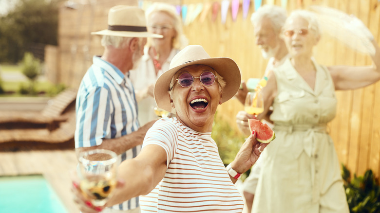 A jubilant group of seniors enjoying sangria by a pool.