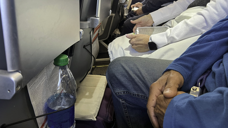 the legs of a row of cramped airline passengers