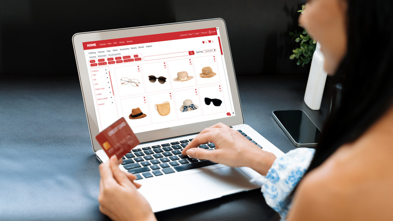 a woman holding a credit card shops on her laptop