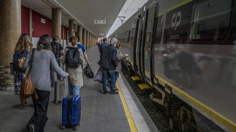 people boarding a train in Portugal with suitcases