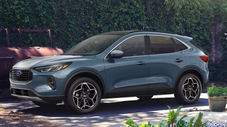 blue-gray Ford Escape parked in front of red smoker grills