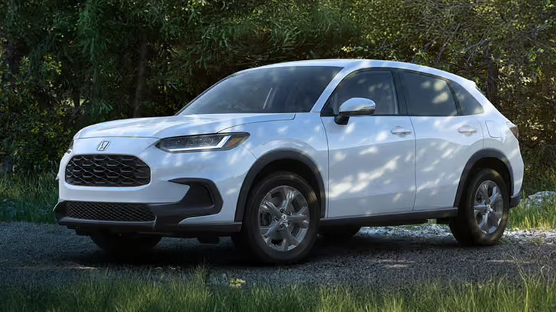 white Honda HR-V parked on gravel in front of wooded area
