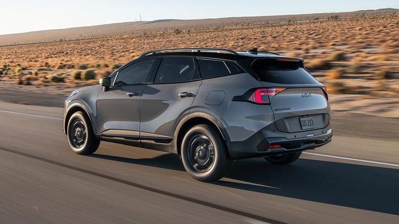 gray Kia Sportage on a desert road