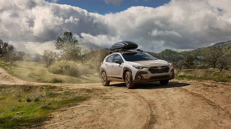 white Subaru Crosstrek travels an isolated dirt road with a rooftop cargo carrier