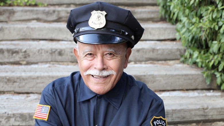 A smiling veteran police officer sitting on stairs.