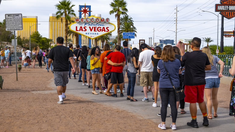 Long line of people in front of "Welcome to Las Vegas" sign