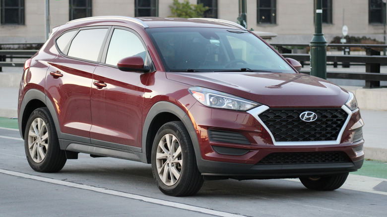 A maroon Hyundai Santa Fe driving on the road.