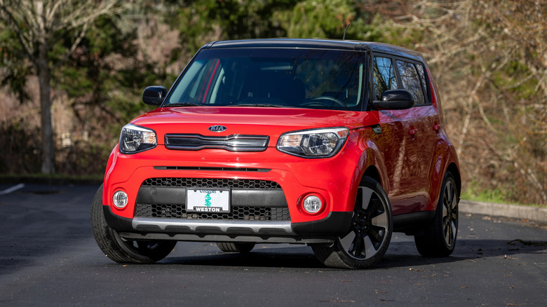 A red Kia Soul South Korean hatchback car parked outdoors in daylight.