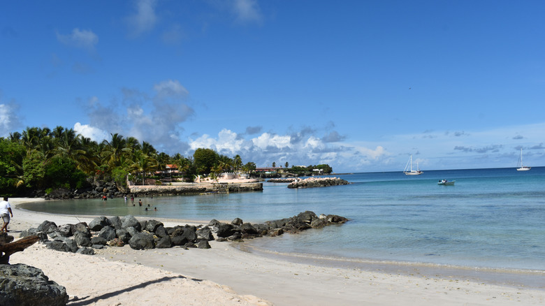 A small group of people enjoying Swallows Beach with small boats in the water