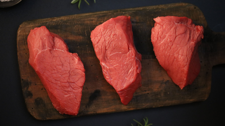 Three petite sirloin steaks on a cutting board.
