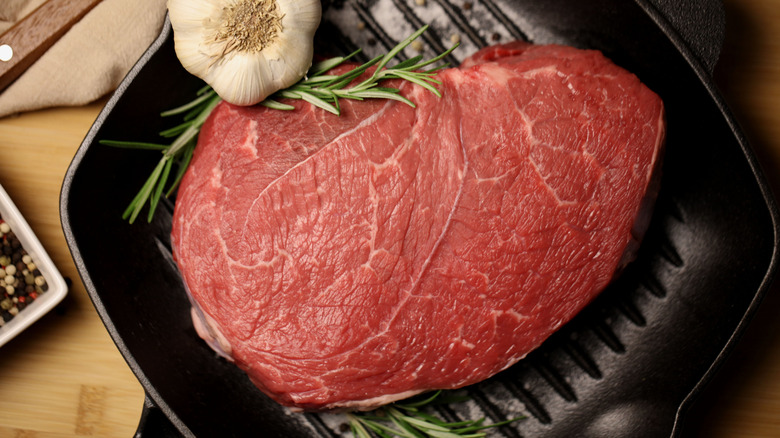 A raw sirloin tip roast in a pan.