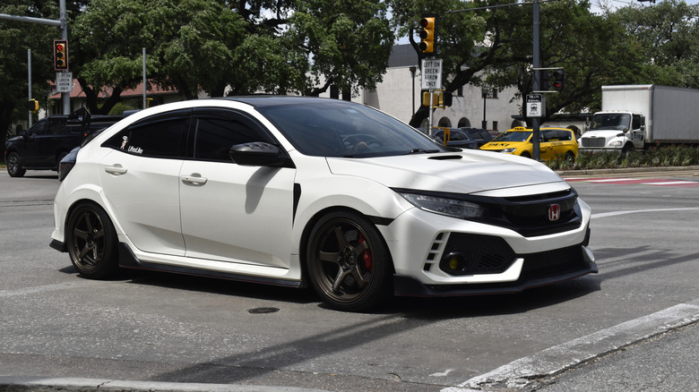A white Honda Civic cruising near Hermann Park in the downtown financial district of Houston.