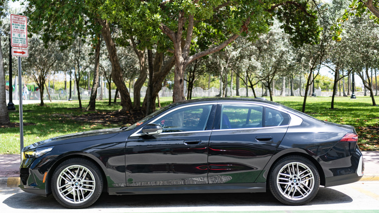 A BMW 5 Series parked in front of a park