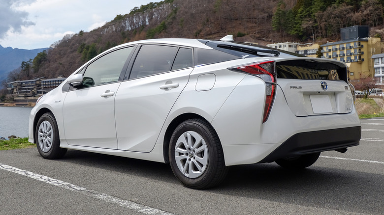 White Toyota Prius parked by a lake in a small town.