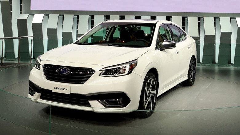 White Subaru Legacy on display at an auto show.