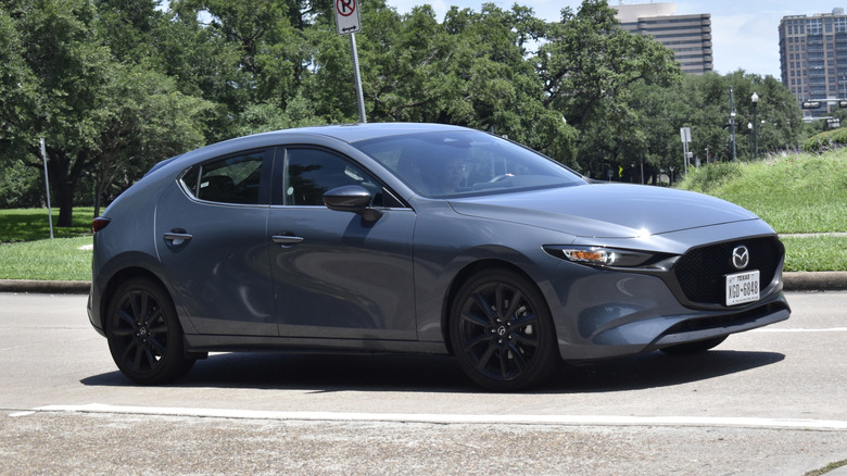 A sleek, Polymetal Gray Mazda3 Hatchback maneuvers through the streets of Houston