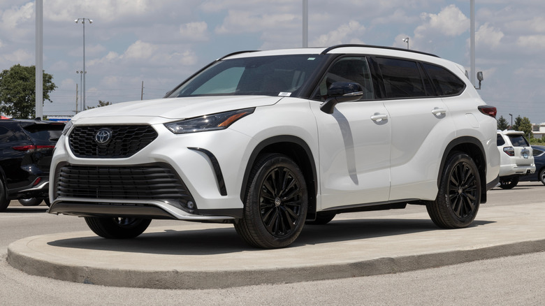 A white Toyota Highlander SUV parked on the curb on a cloudy day.