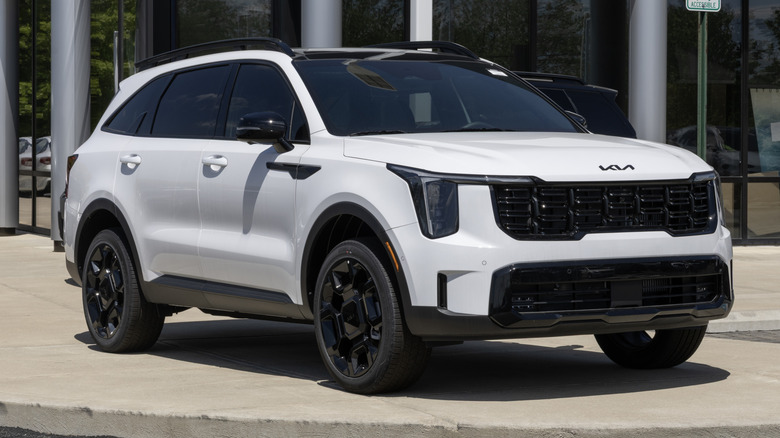 A white Kia Sorento X-Line SX Prestige 2.5T AWD SUV parked outside of a dealership.